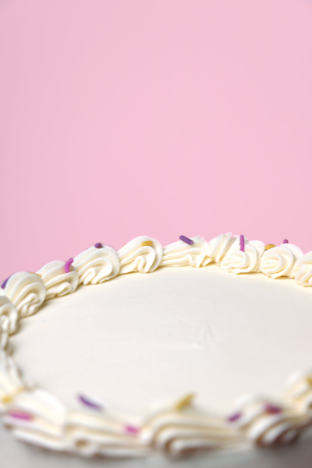 Close up of a Playful birthday cake with piped buttercream candles, pastel sprinkles, and smooth vanilla finish - handmade in Uxbridge by Cakeasion.