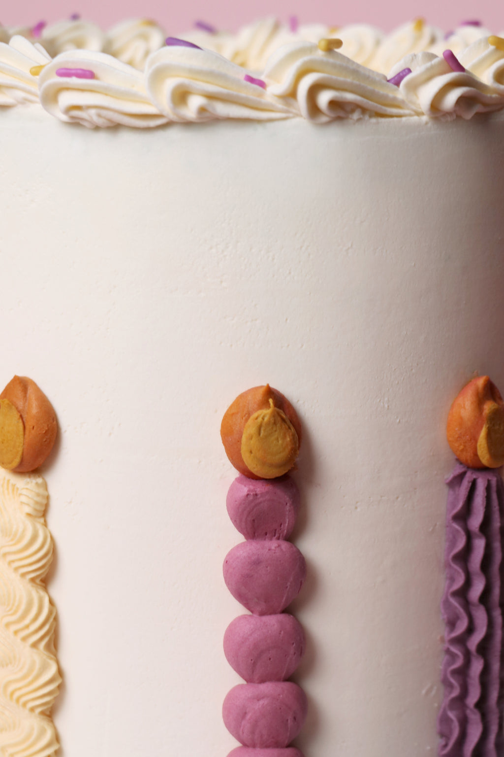 Close up of a Playful birthday cake with piped buttercream candles, pastel sprinkles, and smooth vanilla finish - handmade in Uxbridge by Cakeasion.