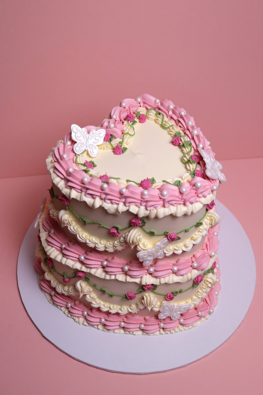Heart-shaped vintage-style birthday cake with piped pink roses and faux pearl details from Cakeasion Shop Uxbridge.