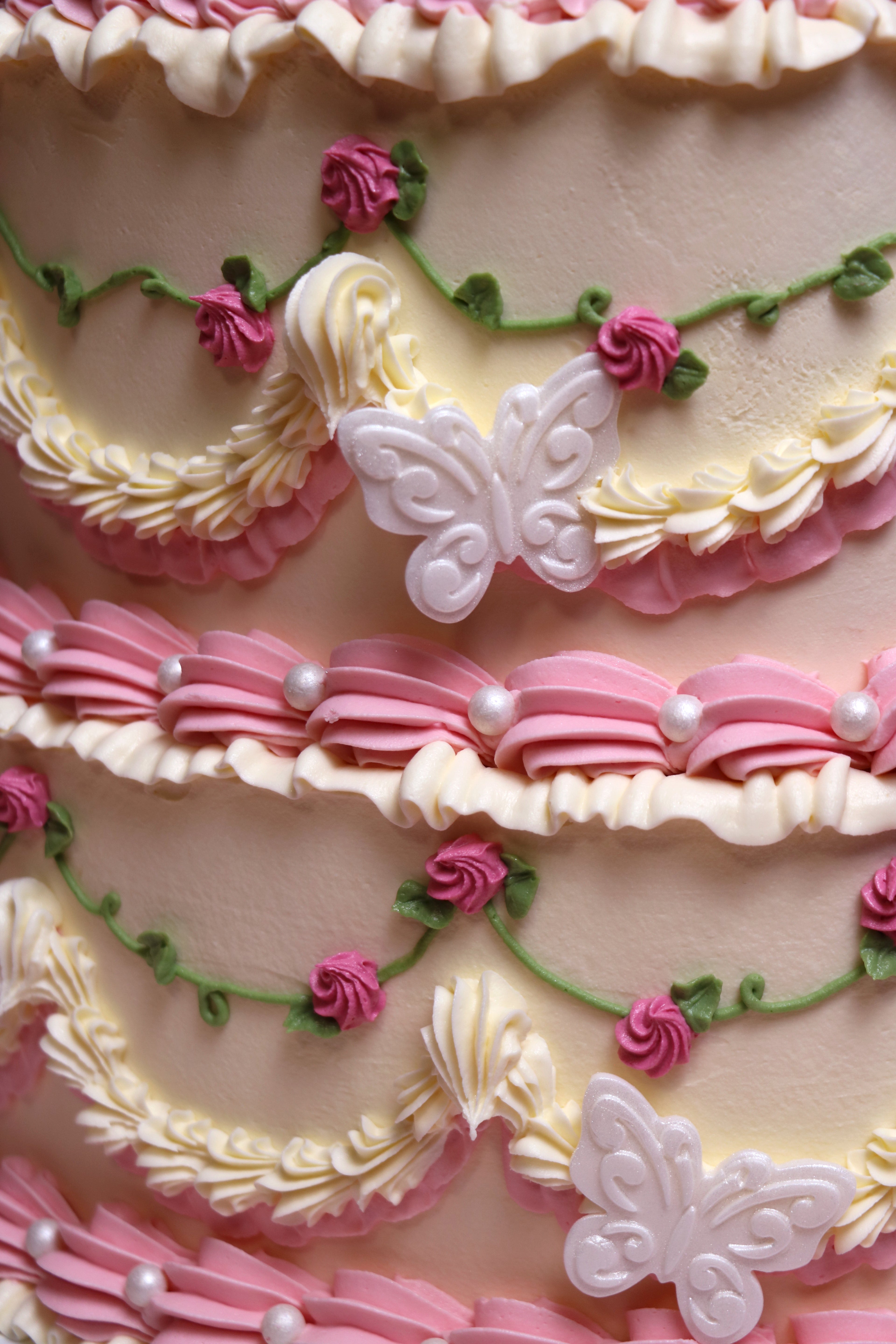 Close up of Heart-shaped vintage-style birthday cake with piped pink roses and faux pearl details from Cakeasion Shop Uxbridge.