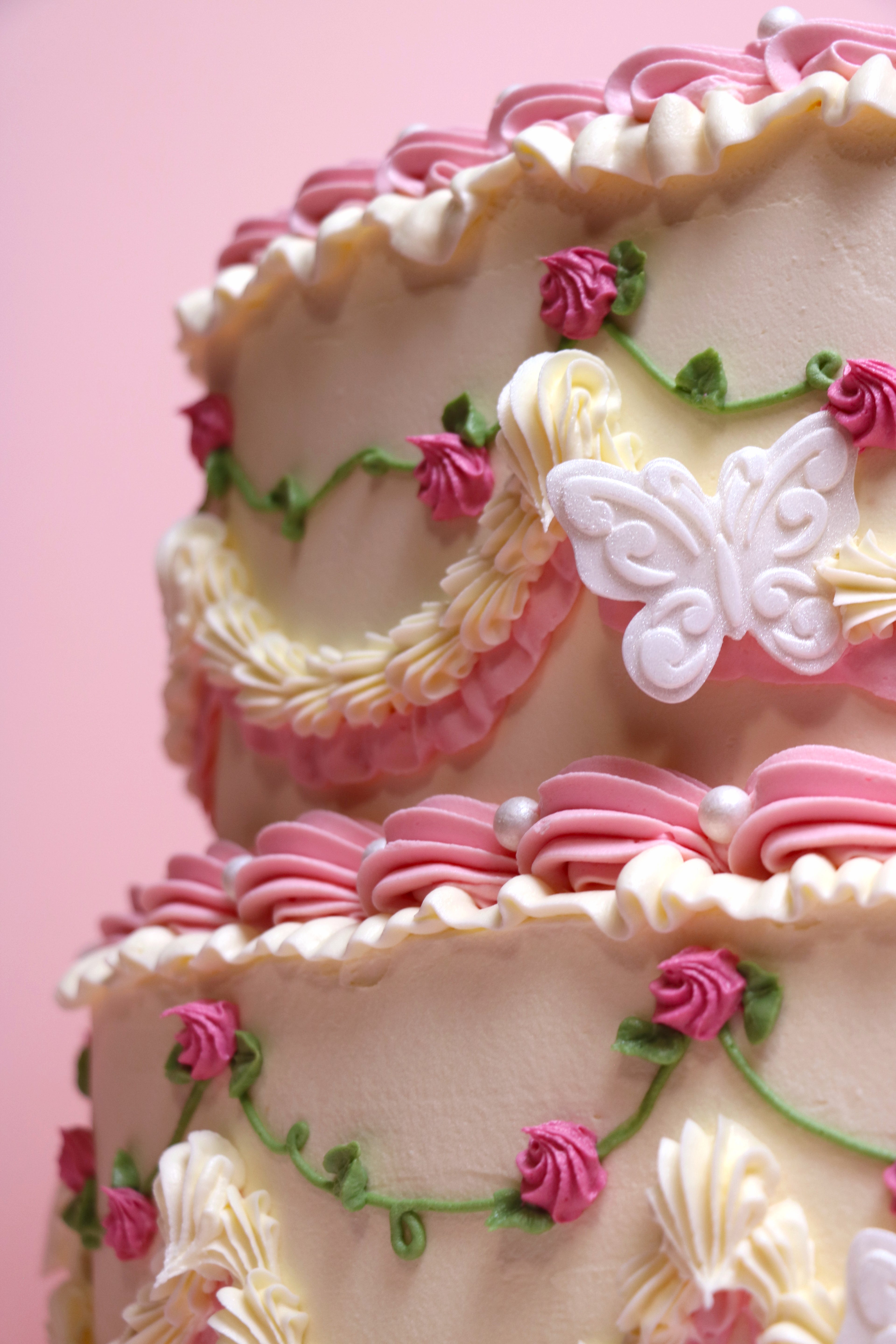 Close up of heart-shaped vintage-style birthday cake with piped pink roses and faux pearl details from Cakeasion Shop Uxbridge.