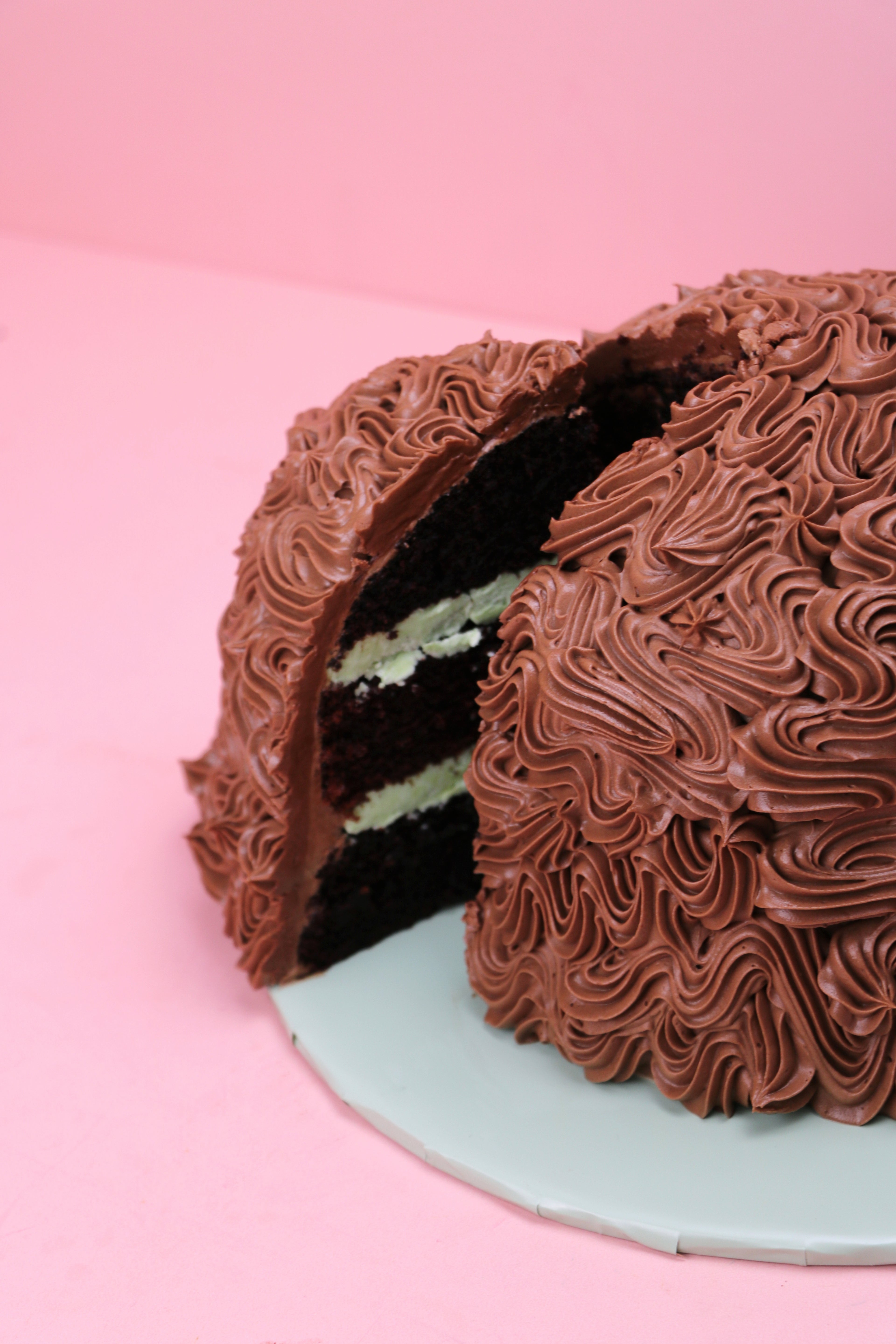Slice cut of a mint chocolate dome cake with piped chocolate buttercream design, Swirl piped chocolate dome cake with mint buttercream filling, Dome-shaped chocolate cake with rich buttercream texture made by Cakeasion in Uxbridge.