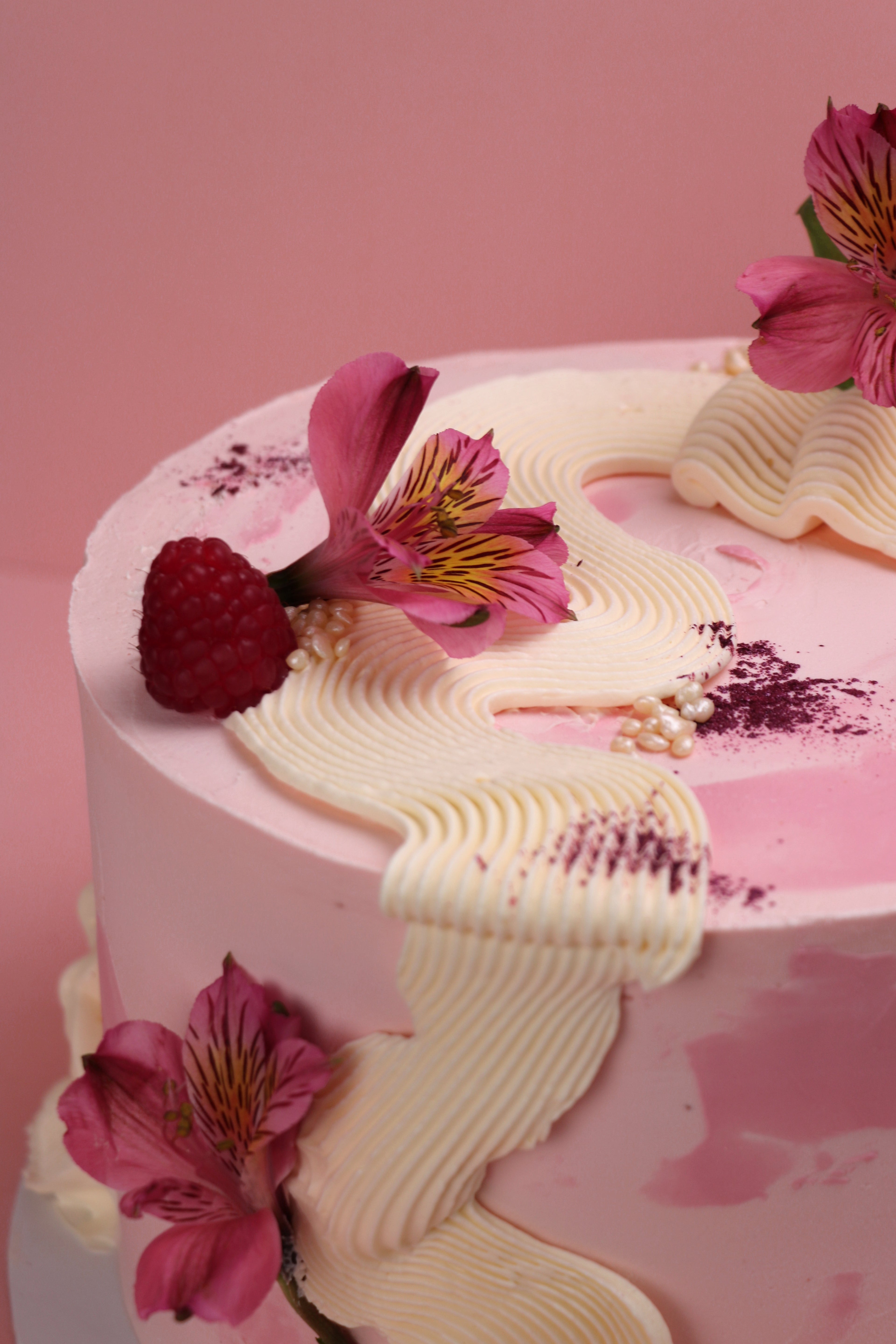 Closeup of vanilla buttercream ribbon piping with fresh alstroemeria flowers and raspberry made by Cakeasion in Uxbridge.