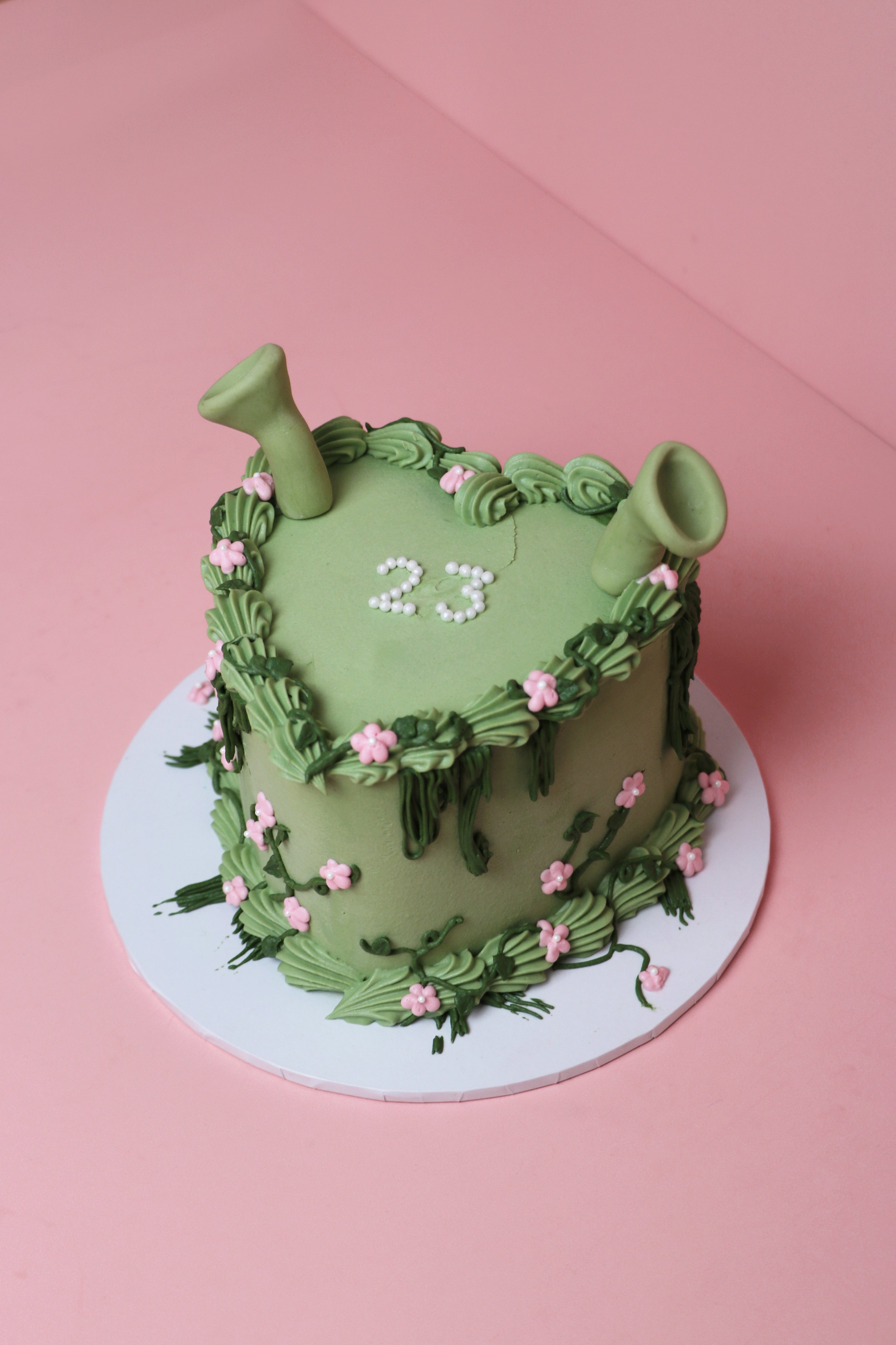 Shrek-themed green floral celebration cake with fondant ears and pink buttercream flowers handmade by Cakeasion in Uxbridge.