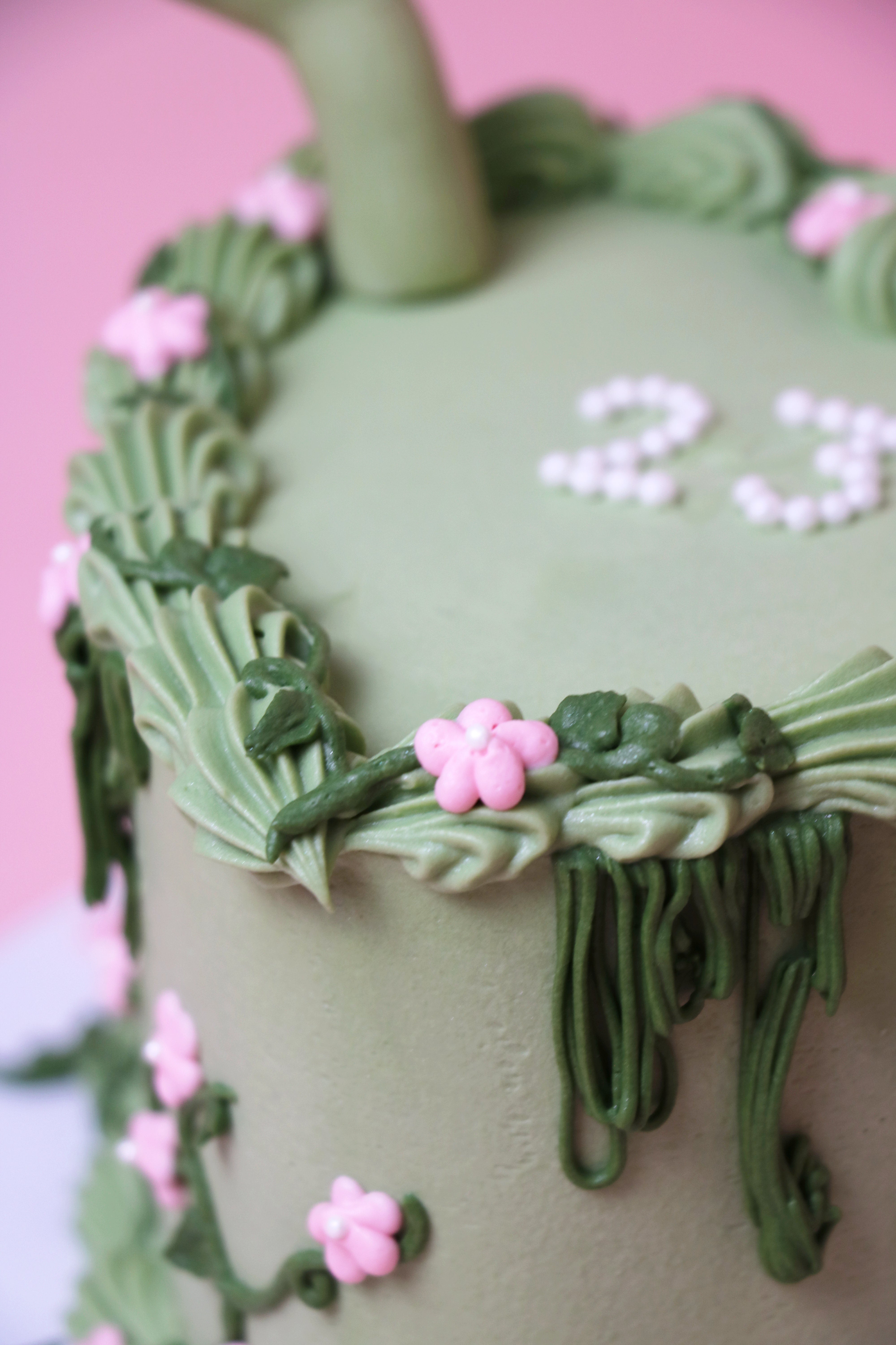 Close up of the Shrek-themed green floral celebration cake with fondant ears and pink buttercream flowers handmade by Cakeasion in Uxbridge.