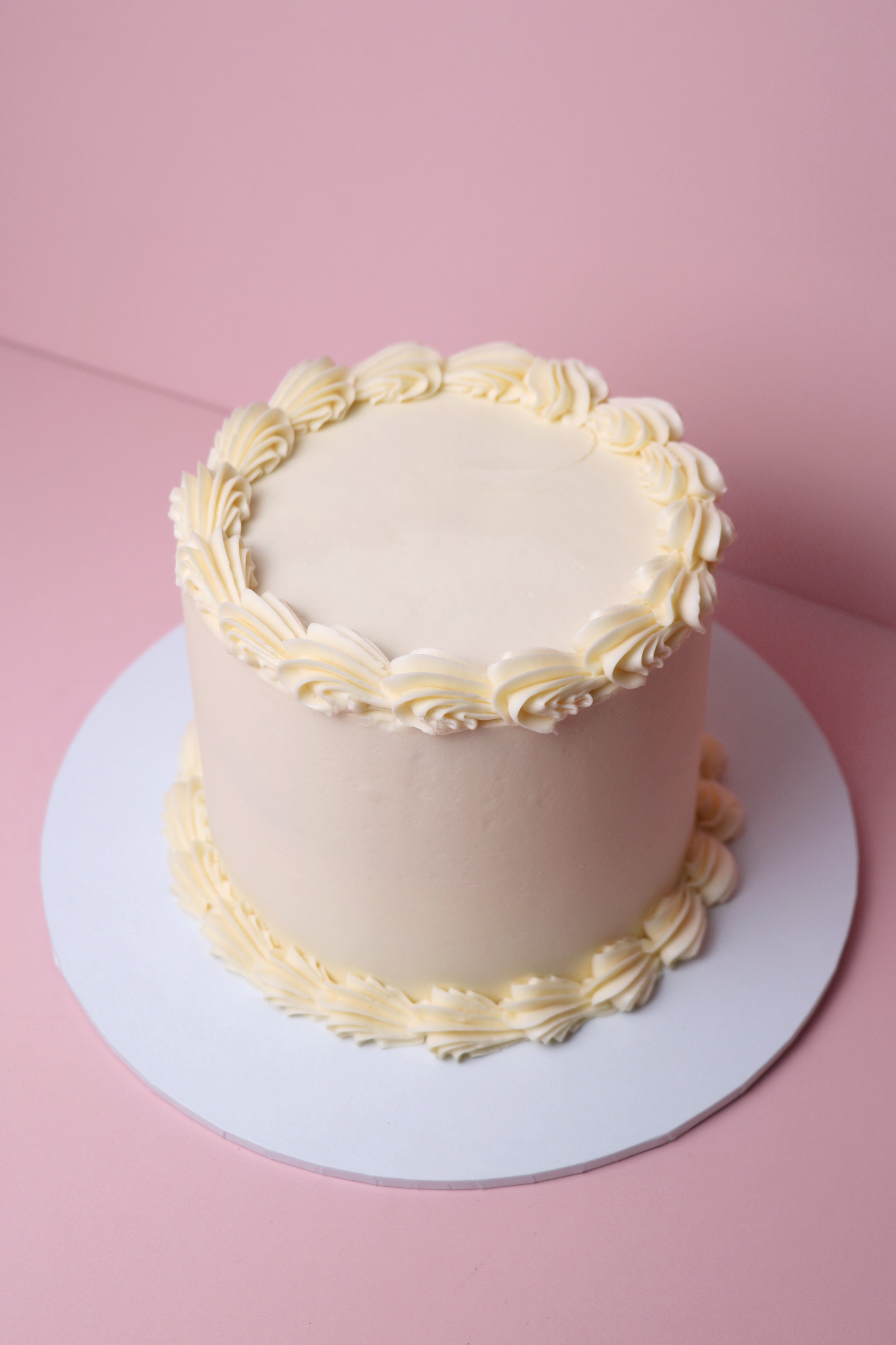 Simple white buttercream cake with piped swirls and a minimalist finish, handmade in Uxbridge by Cakeasion Shop.