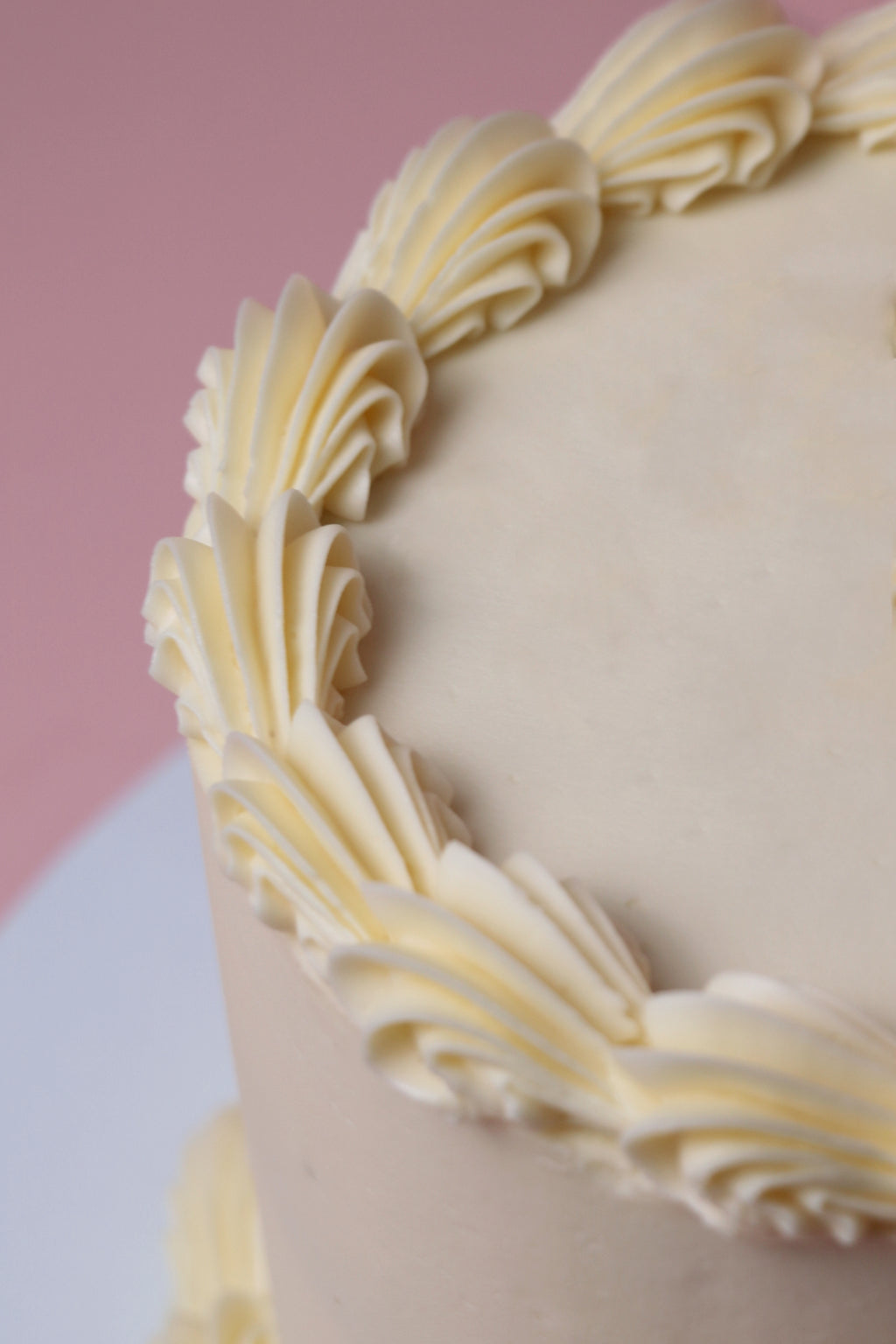 Close-up of a Simple white buttercream cake with piped swirls and a minimalist finish, handmade in Uxbridge by Cakeasion Shop.