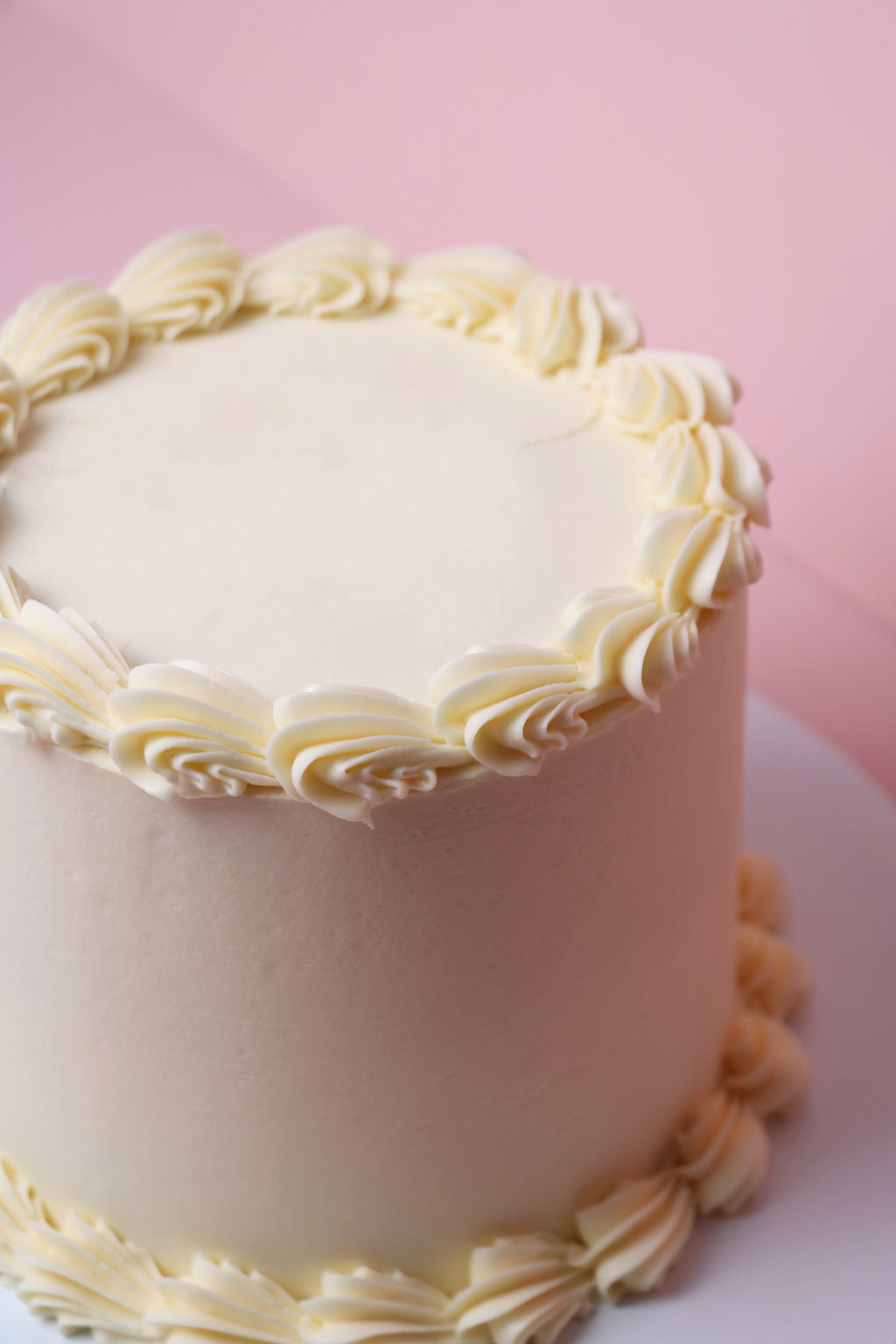 Simple white buttercream cake with piped swirls and a minimalist finish, handmade in Uxbridge by Cakeasion Shop.
